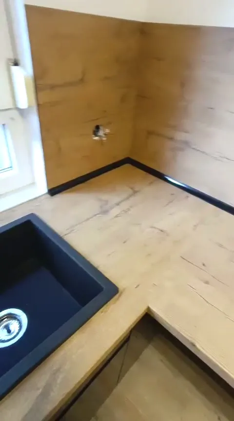 Video: schwarze Spüle in einer Eck-Arbeitsplatte in Eiche-Optik mit passender Rückwand