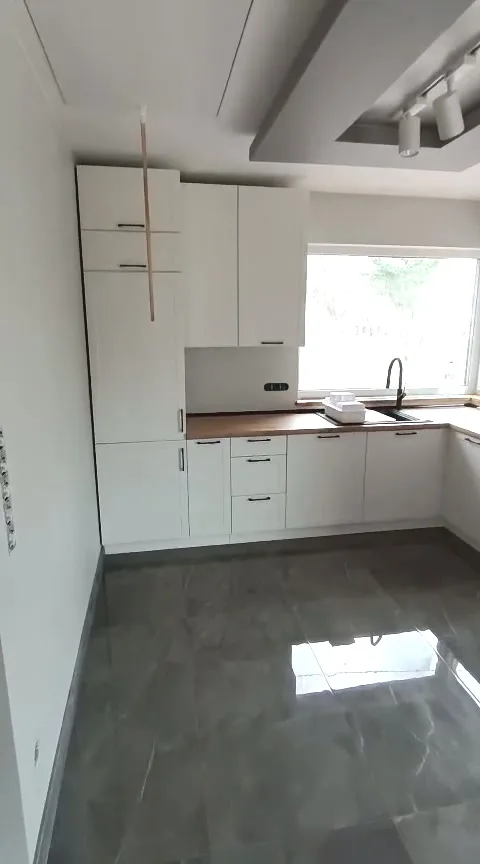 Video: weiße Eckküche mit Hochschränken, Arbeitsplatte in Nussbaumoptik und breitem Fenster