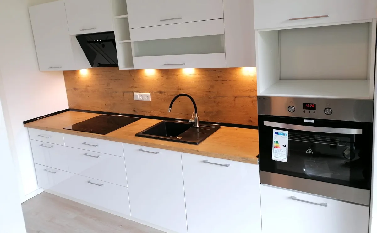 Weiße Küchenzeile mit Arbeitsplatte und Rückwand in Eiche-Optik, Nische über dem Backofen